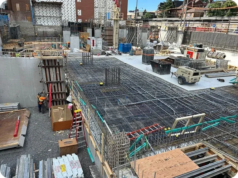 Crew pouring concrete and placing rebar at a Toronto urban high-rise foundation