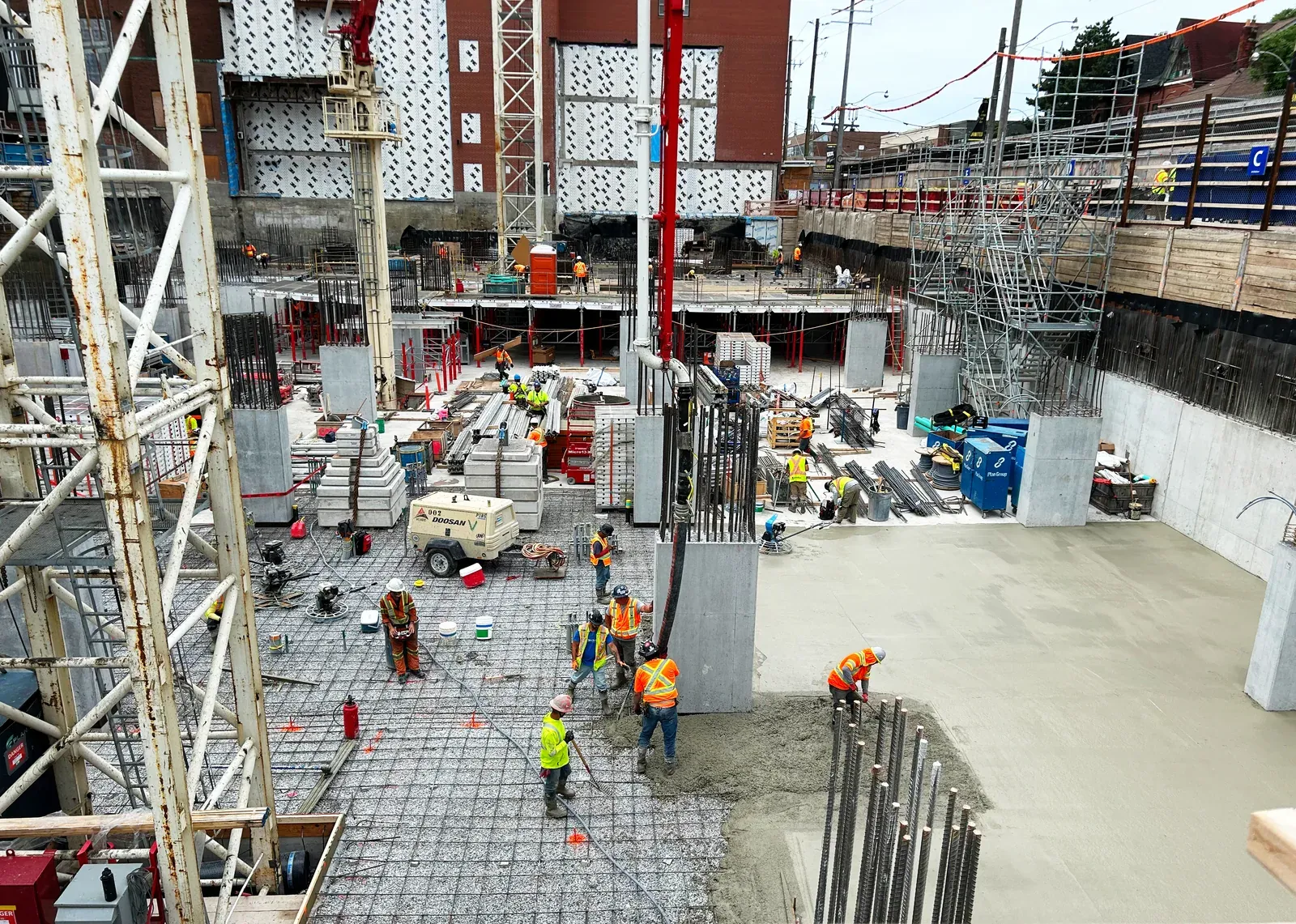 Urban Toronto construction site with crew tying rebar and placing foundation slab