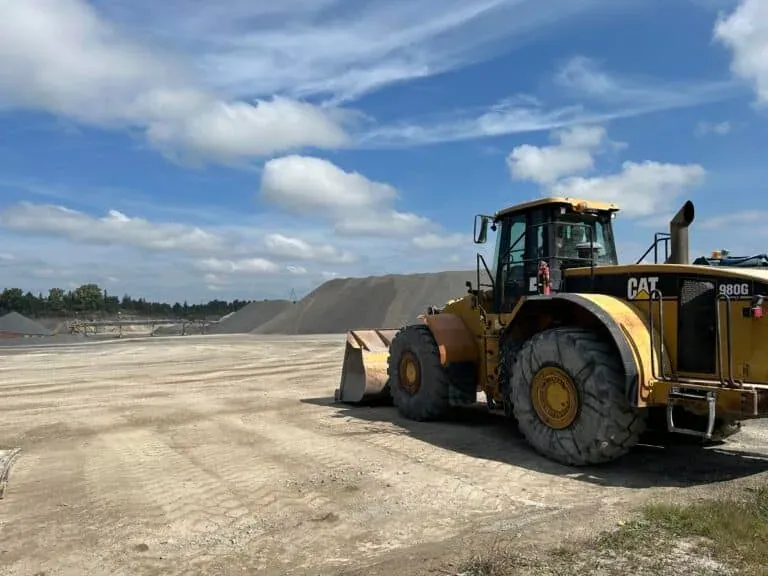 A large wheel loader sits on a prepared aggregate surface under a blue sky at an active construction or quarry site. The image symbolizes modern construction operations, efficiency, and the day-to-day environment where digital tools like Crewscope support crews and site leaders.