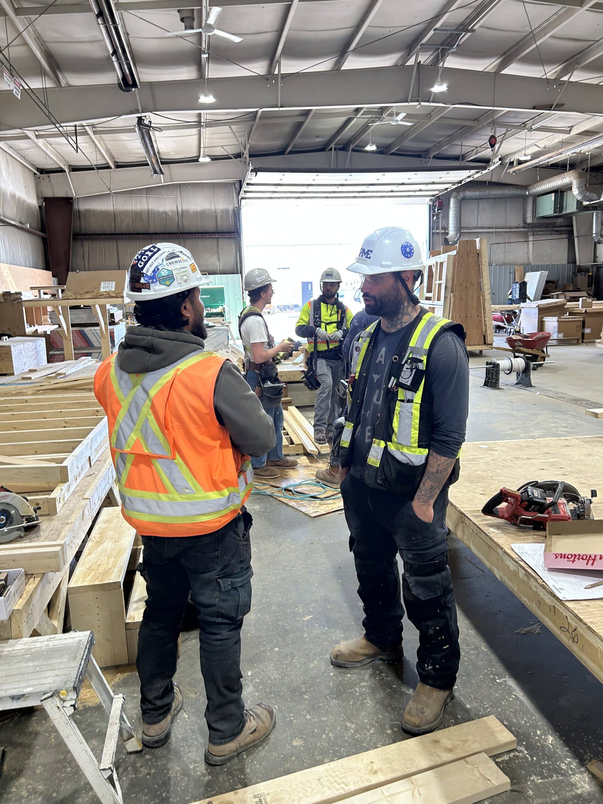 Carpenters discussing workplans in a prefabrication facility.